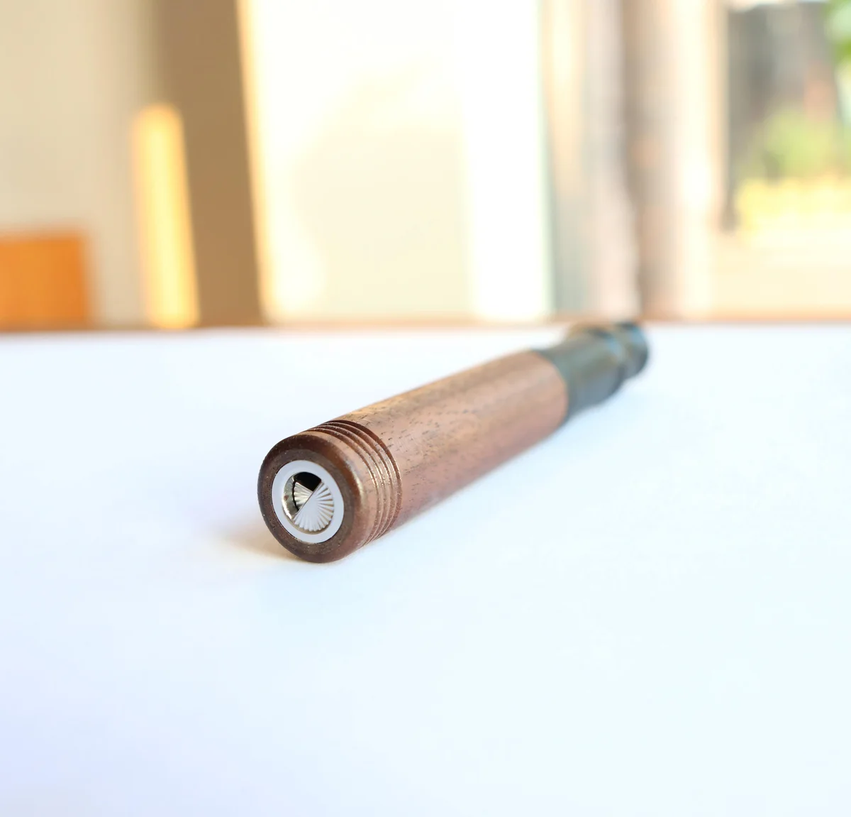 AIRITU R-W000 wood-shell aromatic inhaler on a white tabletop with its base end closest to the camera
