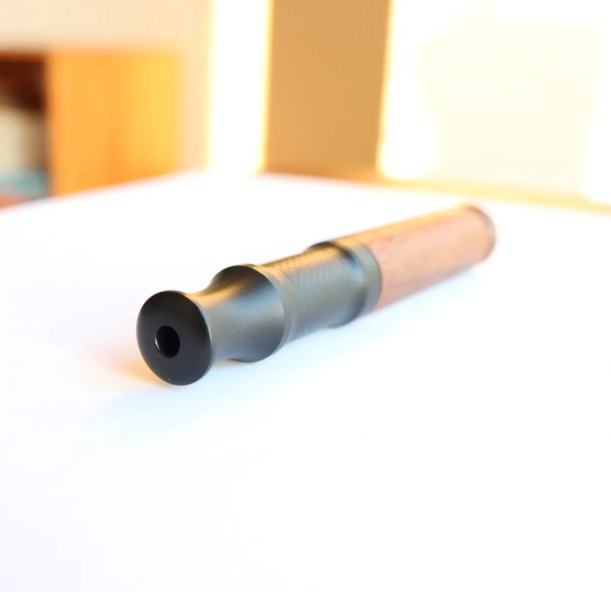 AIRITU R-W000 wood-shell aromatic inhaler on a white tabletop with the dark mouthpiece opening facing the camera